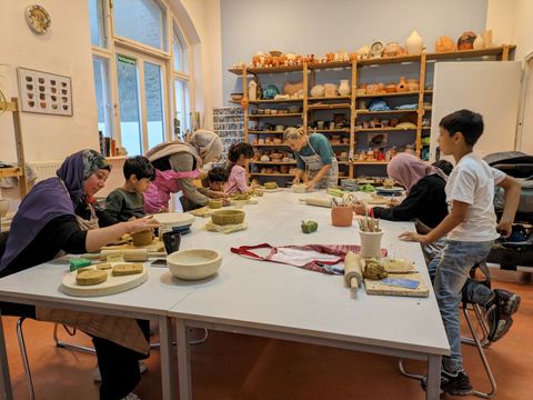 Mütter mit ihren Kindern sitzen an einem Tisch und töpfern.