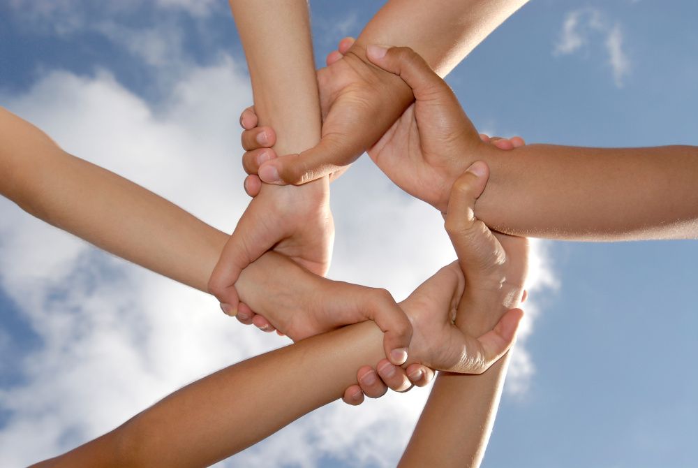 Mehrere Hände greifen ineinandern und bilden einen Ring