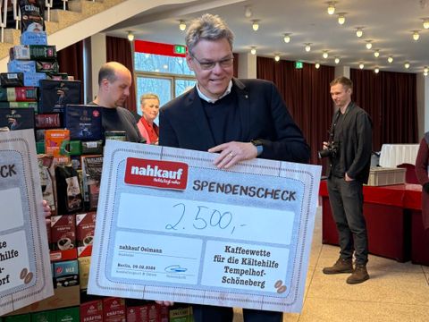 Bezirksbürgermeister Jörn Oltmann hält einen Spendenscheck in Höhe von 2.500 Euro für die Kältehilfe Tempelhof-Schöneberg.