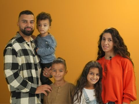 Auf dem Bild ist eine fünfköpfige Familie in einer Interview Situation zu sehen.