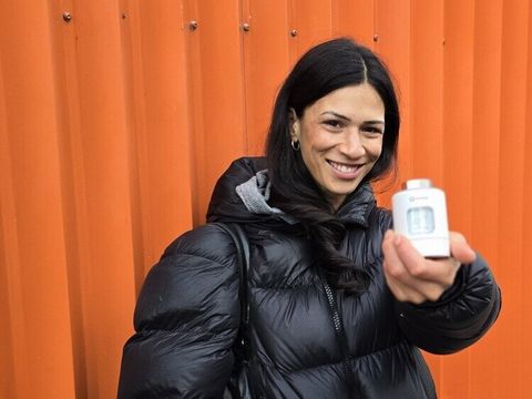 Zoe Naomi Hoffmann, Klimaschutzmanagerin in der OE Klima und Internationales, zeigt ein smartes Themostat vor dem Gebäude in der Ohlauer Straße