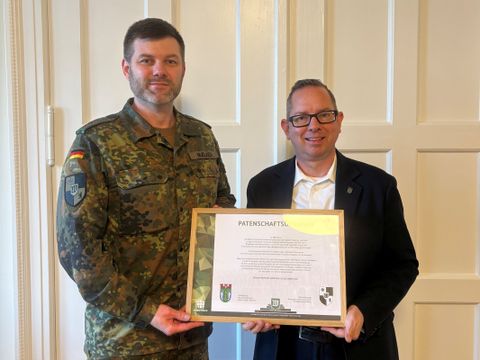 Kompaniechef und Bezirksbürgermeister halten die aktualisierte Urkunde in der Hand