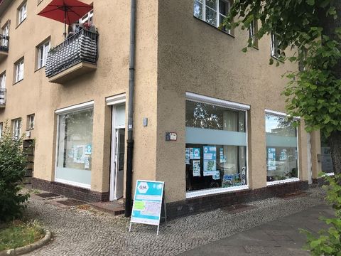 An einer Hausecke vor einem Ladenbüro steht ein Aufsteller mit dem Logo QM.