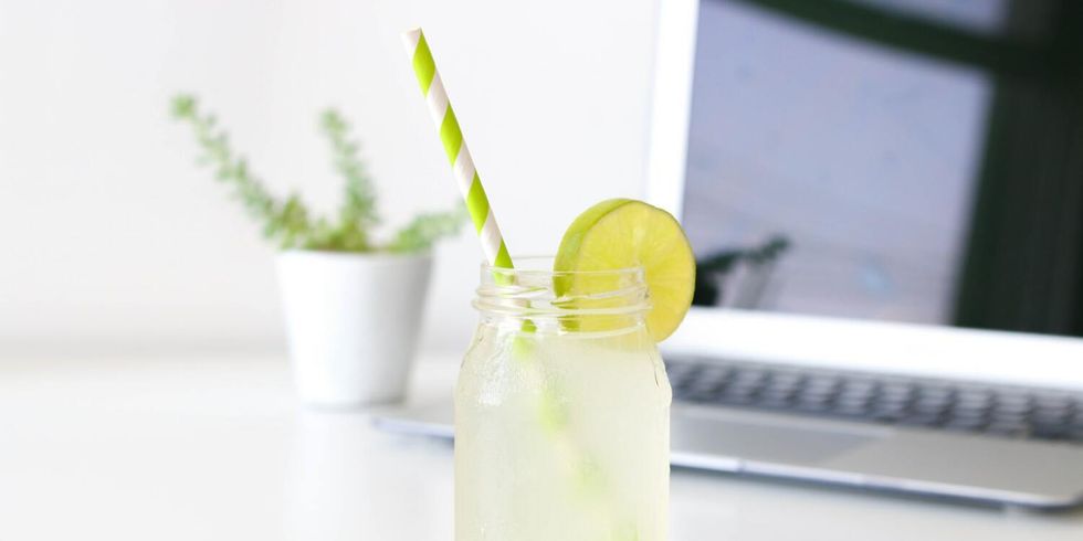 Eine kalte Limonade steht auf dem Arbeitstisch, im Hintergrund ein Laptop.