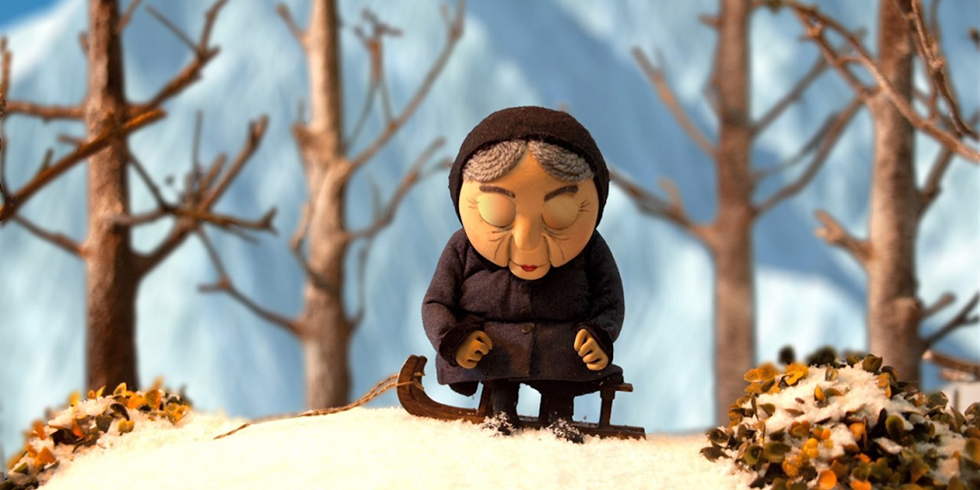 Ausschnitt eines Animationsfilms; eine ältere Frau sitzt seitlich auf einem Schlitten in einer zugeschneiten Landschaft. Sie hat die Augen geschlossen und den Kopf zum Boden geneigt.