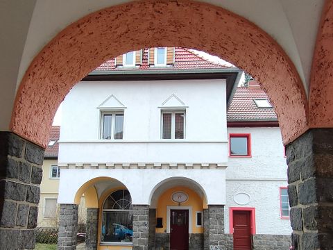 Haus in weiß und rosa sichtbar durch einen Torbogen