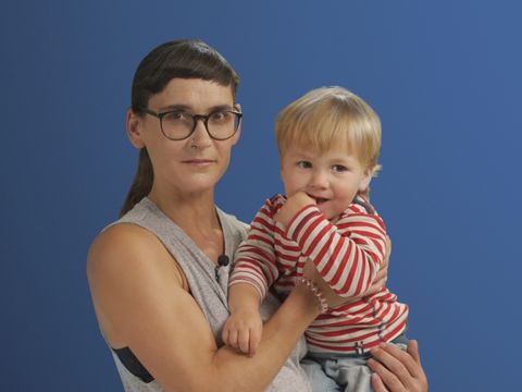 Auf dem Bild ist eine Alleinerziehende mit ihrem Sohn auf dem Arm in einer Interview Situation zu sehen