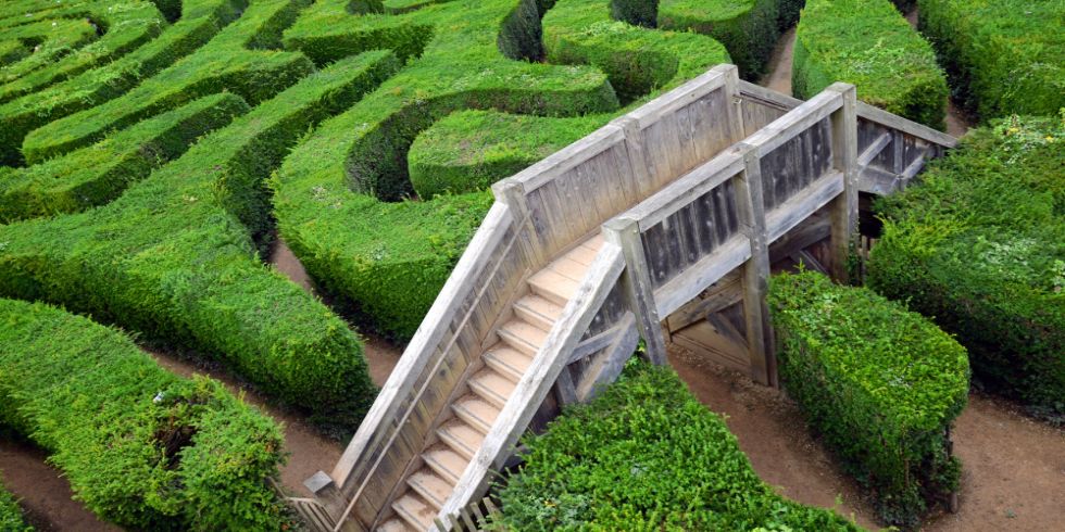 Eine Holzbrücke über einem grünen Labyrinth