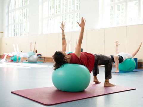 Person auf Gymnastikball mit Blick zur Decke