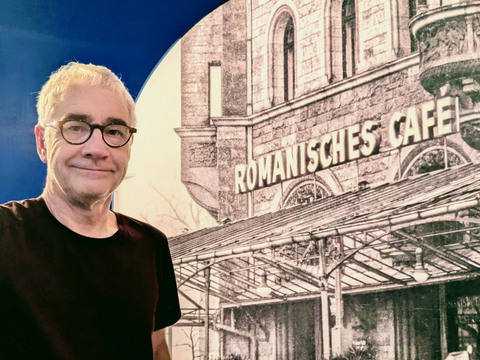 Michael Bienert vor einem Bild, das das Romanische Café zeigt