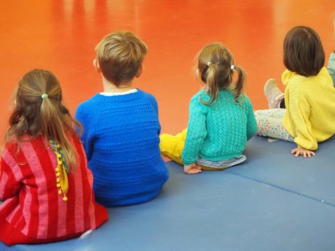 Kinder sitzen auf einer Matte