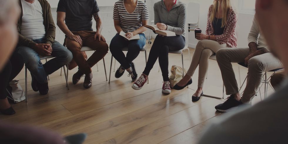 Menschen sitzen auf Stühlen in einem Kreis und diskutieren