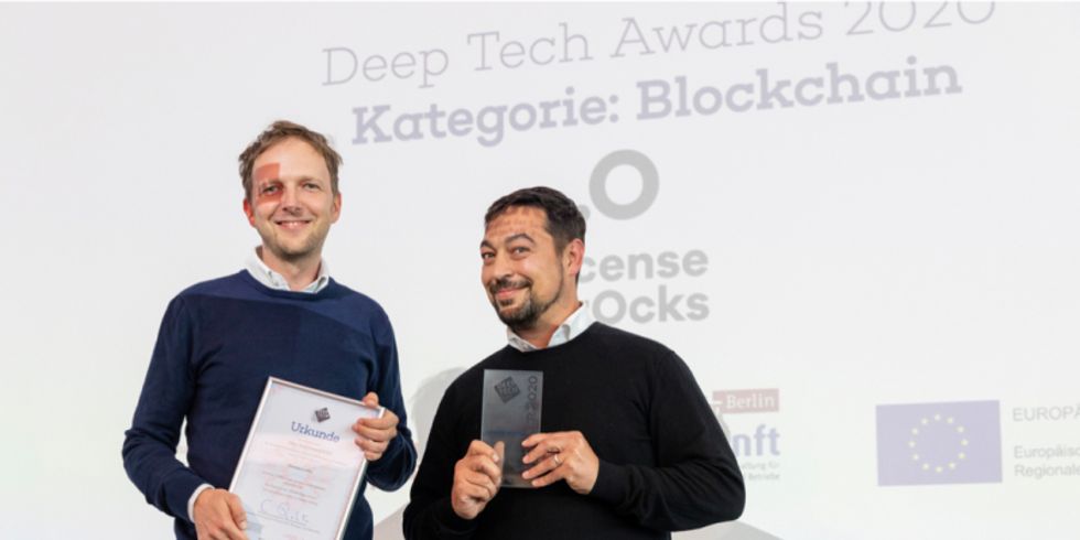 Zwei Männer halten Award und Urkunde hoch und lachen in die Kamera