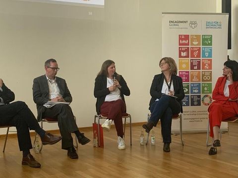 Mehrere Personen in einer Diskussionsrunde, Frau Herrmann in der Mitte