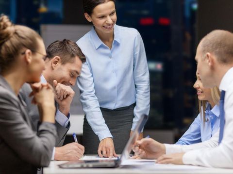 smiling female boss talking to business team