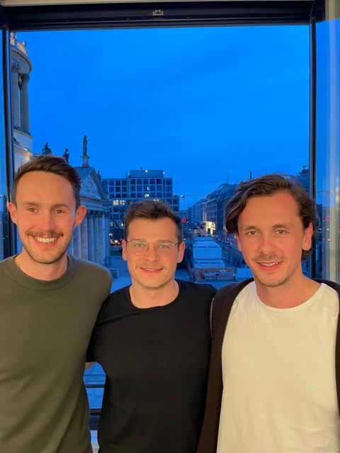Gruppenbild von Gründerteam Jack Lancaster, Carl Brenssell, Max Brenssell vor einem Fenster, mit Gebäuden im Hintergrund