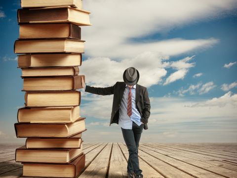 Ein Mann lehnt an einem großen Bücherstapel