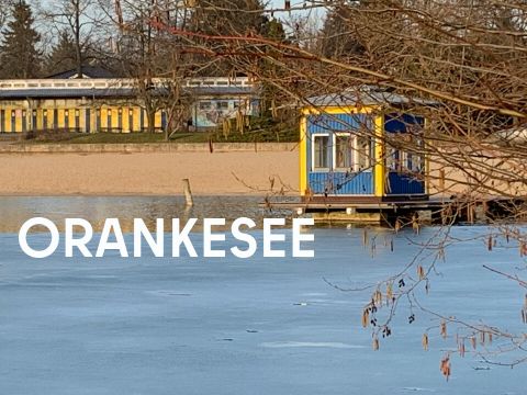 zugefrorener See und blaues Badehäuschen und Strand im Hintergrund