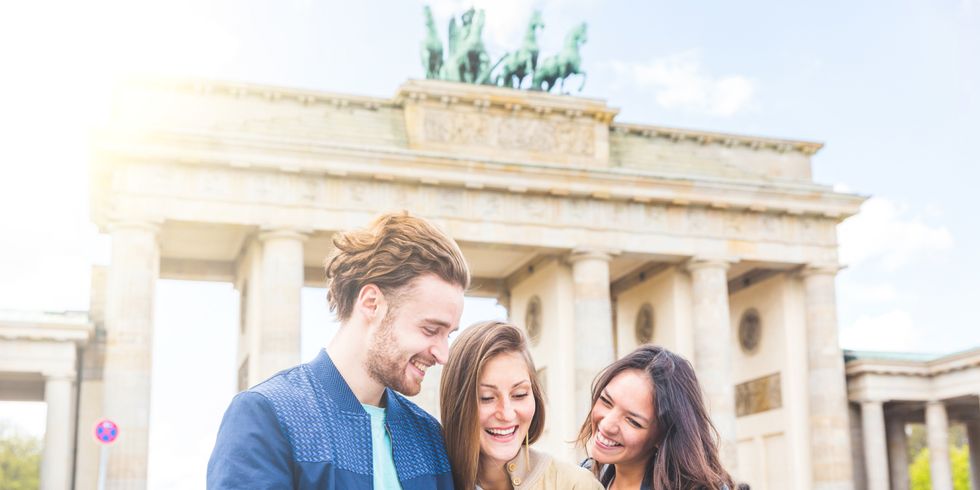 Eine Gruppe von Freunden schaut vor dem Brandenburger Tor auf einen Stadtplan