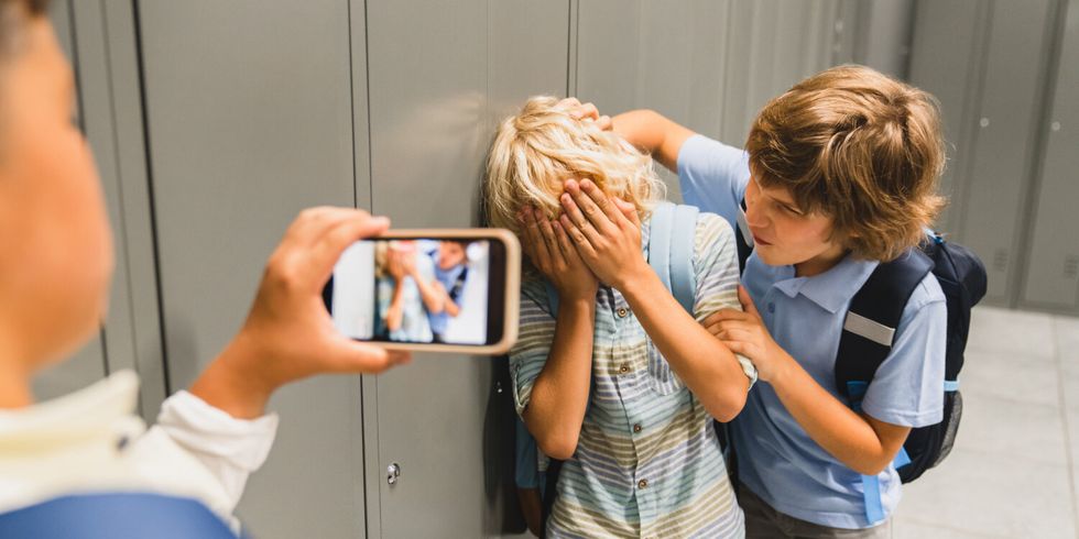 Schüler filmen mit dem Handy, wie sie ihren Mitschüler in der Schule schikanieren.