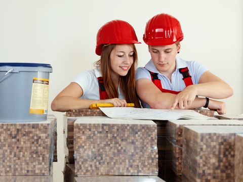 Junge Arbeiter mit Schutzhelm, die ein Haus planen