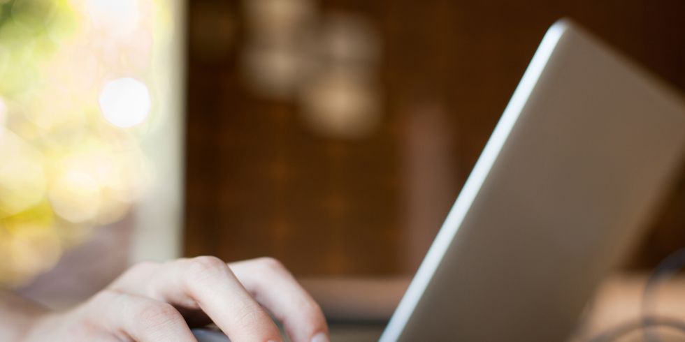 Hand auf der Maus neben einem Laptop