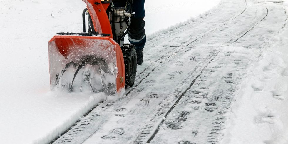 Ein Mann arbeitet mit einer Schneefräse, um frisch gefallenen Schnee von einer Hochspannungstransformator-Einfahrt zu entfernen