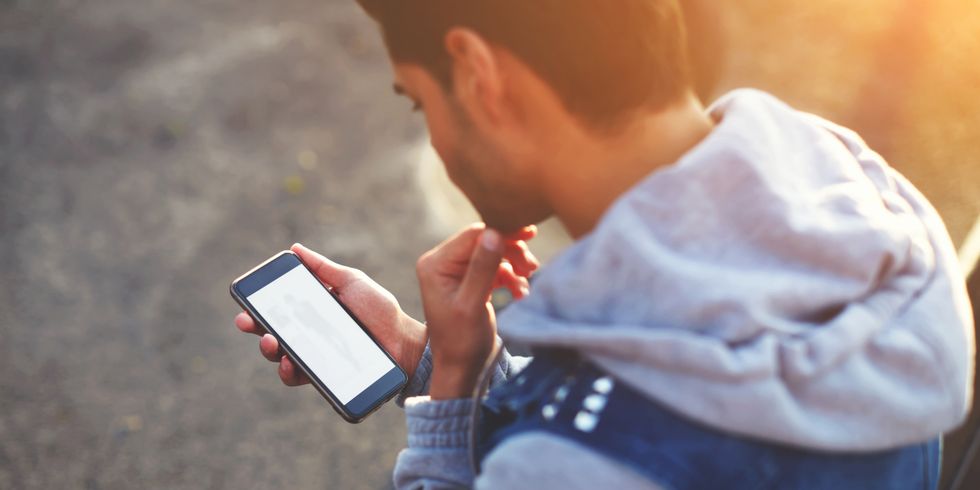 junger Mann schaut auf sein Smartphone