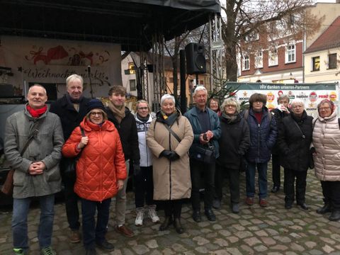 Vollversammlung vor der Weihnachtsmarktbühne: 1.v.l. Christian Urlaub, Partnerschaftsbeauftragter 3.v.l. Gisela Pflug, stv. Vorsitzende Partnerschaftsverein 4.v.l. Sebastian Leskien, Vorsitzender Partnerschaftsverein 5.v.l. Katrin Kunipatz, Pressesprecherin Stadt KW 6.v.l. Michaela Wiezorek, Bürgermeisterin KW 7.v.l. Heinz-Joachim Elbe, Vorstandsmitglied Partnerschaftsverein 3.v.r. Rosemarie Menzel, Vorstandsmitglied Partnerschaftsverein