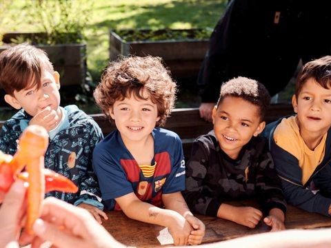 4 Kinder sitzen auf einer Bank an einem Tisch