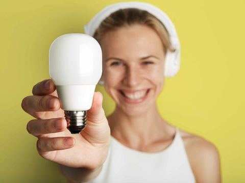 Blonde Frau hält Glühlampe in der Hand.