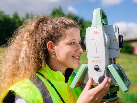 Vermessungstechnikerin schaut in ihr Messgerät