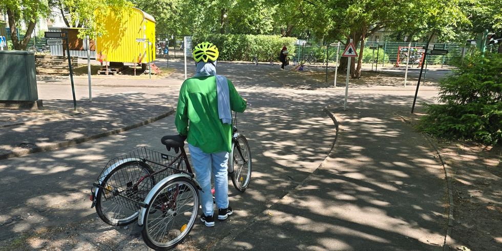Eine Frau versucht sich während ihrer ersten Fahrstunde zunächst auf einem Dreirad für erwachsende Fahrer*innen bevor sie auch auf zwei Rädern das Fahren versucht