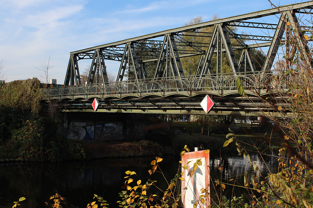 Aufnahme der Späthstraßenbrücke in Neukölln mit Uferanschnitt, Schifffahrtsschild und Zweige im Vordergrund