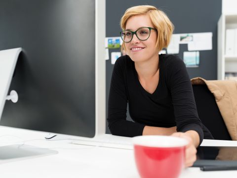 Blonde junge Frau trinkt Kaffee bei der Arbeit
