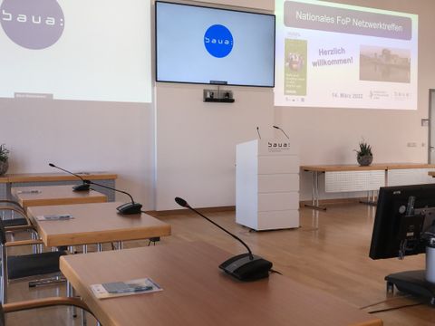 Foto vom Veranstaltungstag des nationalen Focal Point (FoP) der EU-OSHA mit Stehpult, Bildschirm und Folienpräsentation