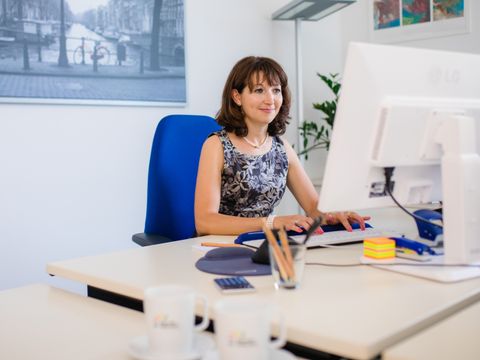 Mitarbeiterin tippt auf der Tatstatur an ihrem Schreibtisch