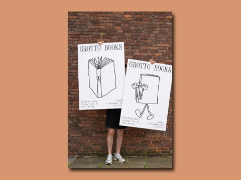 Mann hällt zwei Plakate von Grotto Books