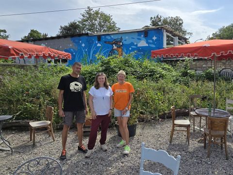 Dunja und Lothar Zech stehen gemeinsam mit Clara Herrmann (Mitte) vor dem Eisvogel-Grafitti des Künstlers Marc Seven im Naturgarten-Café am Ostkreuz