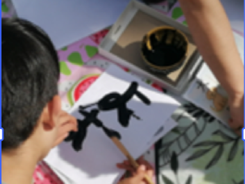 Ein Kind schreibt mit einem Pinsel ein japanisches Schriftzeichen