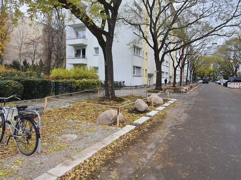 Entsiegelte Flächen um Bäume mit Steinen und gespanntem Seil als Abgrenzung