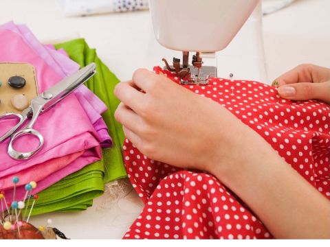 angedeutete Nähmaschine und zwei Hände, die Stoff nähen