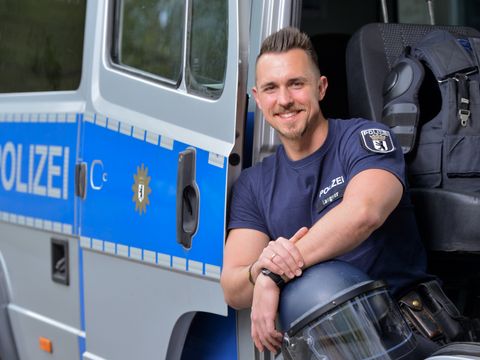Polizist sitzt vor einem Einsatzfahrzeug