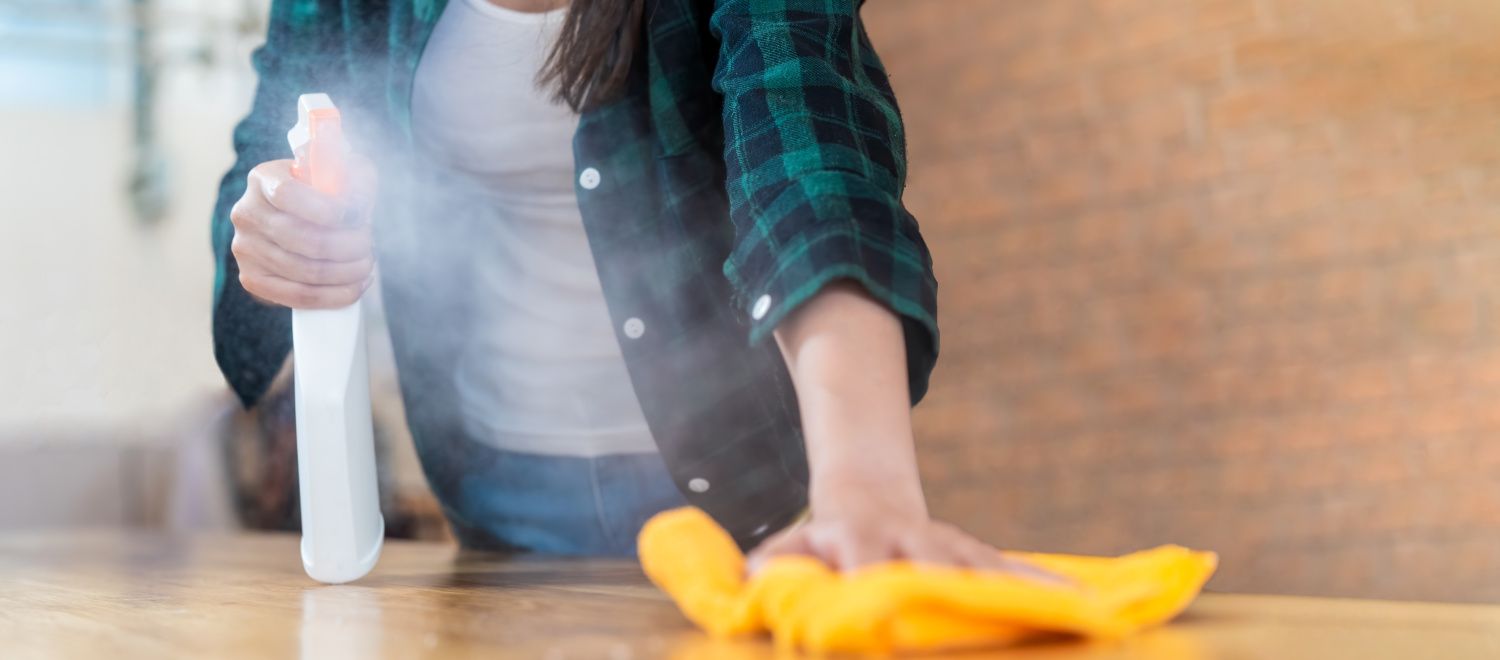 Frau reinigt Tischoberfläche im Restaurant mit Desinfektionsmittel und Lappen