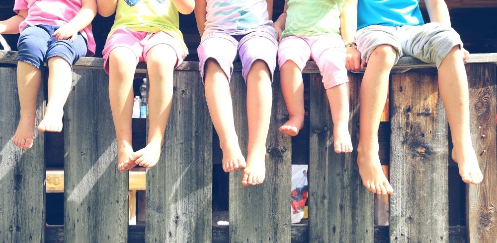 Kinderbeine bäumeln über einem Zaun