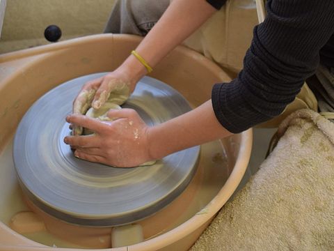 Gestalten in Keramik: Ein Kind formt ein Gefäß aus Ton an der Drehscheibe. (Bild: © Jugendkunstschule Pankow)