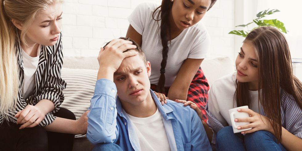 Junge Leute trösten ihren aufgebrachten Freund, diskutieren Probleme zu Hause