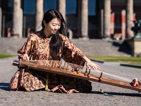 Musikerin Hyunjeong Park spielt Gayageum vor dem Alten Museum in Berlin