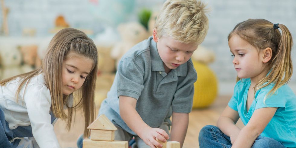 drei Kleinkinder spielen mit Holzklötzen