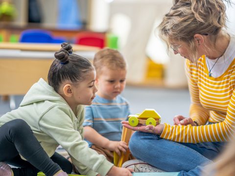 junge Frau spielt mit zwei Kleinkindern